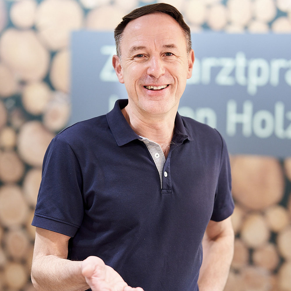 Jochen Holz, Zahnarzt in Wetzlar, trägt ein blaues Poloshirt und lächelt in die Kamera.